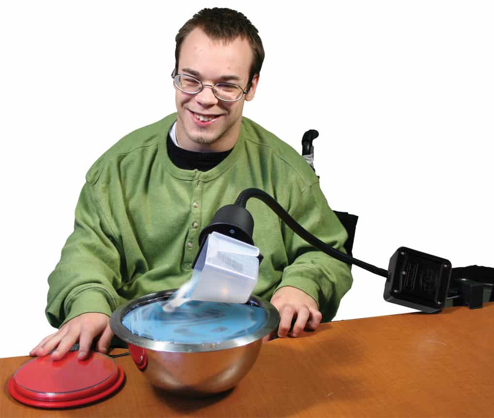 Person using a specialized device with a bowl and red component on a table. Special Needs Computers.