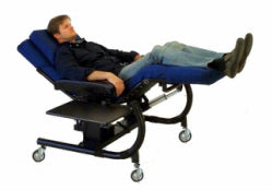 A reclining medical-style examination table with a person lying on it, shown against a plain white background. Zero Gravity Office Chair 1 Special Needs Computers