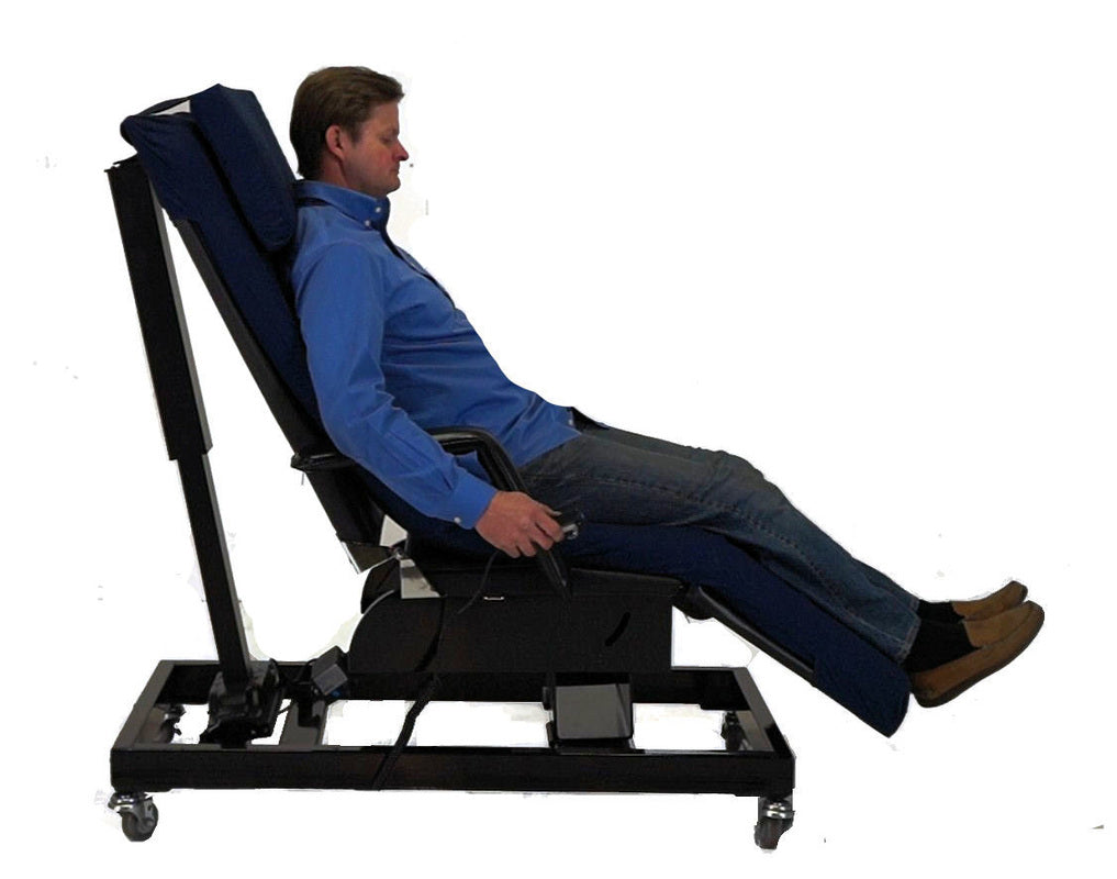 A man reclining in a black and navy adjustable medical-style chair with a wheeled base, shown against a plain white background. Zero Gravity Chair 5 Special Needs Computers.ca