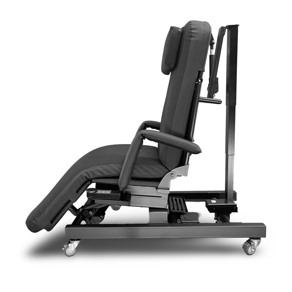 A dark gray adjustable medical or therapy reclining chair with a headrest, armrests, and a wheeled base, shown in side profile against a white background. Zero Gravity Chair 4 Special Needs Computers.