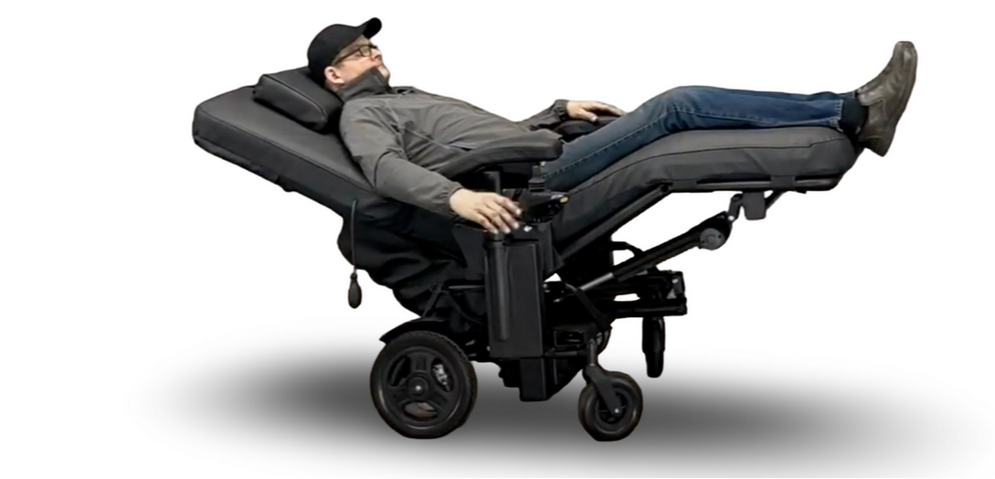 Man using a specialized wheelchair with reclined position on a white background. Ergoquest Zero Gravity Power Chair Special Needs Computers.