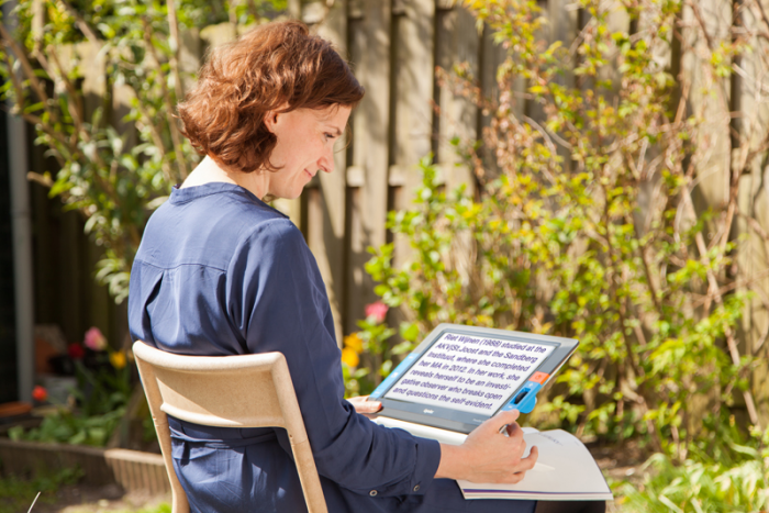 Optelec Traveller HD Portable Video Magnifier Woman sitting outside reading a book