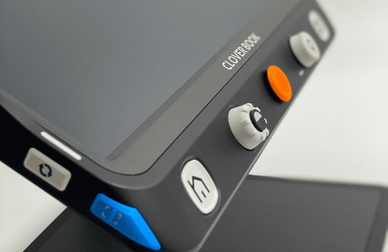 Close-up of a CloverBook device showing its dark gray bezel, white control buttons, an orange button, and a blue button on a light gray background. CloverBook XL Special Needs Computers in Canada.