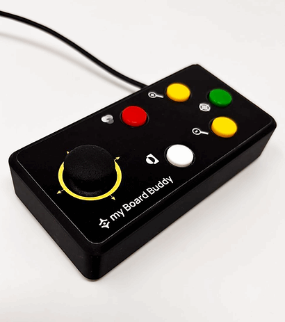 A black handheld electronic control device labeled 'my Board Buddy' with a large black joystick, yellow and green buttons, a red button, and a white button, shown on a plain light background. Special Needs Computers