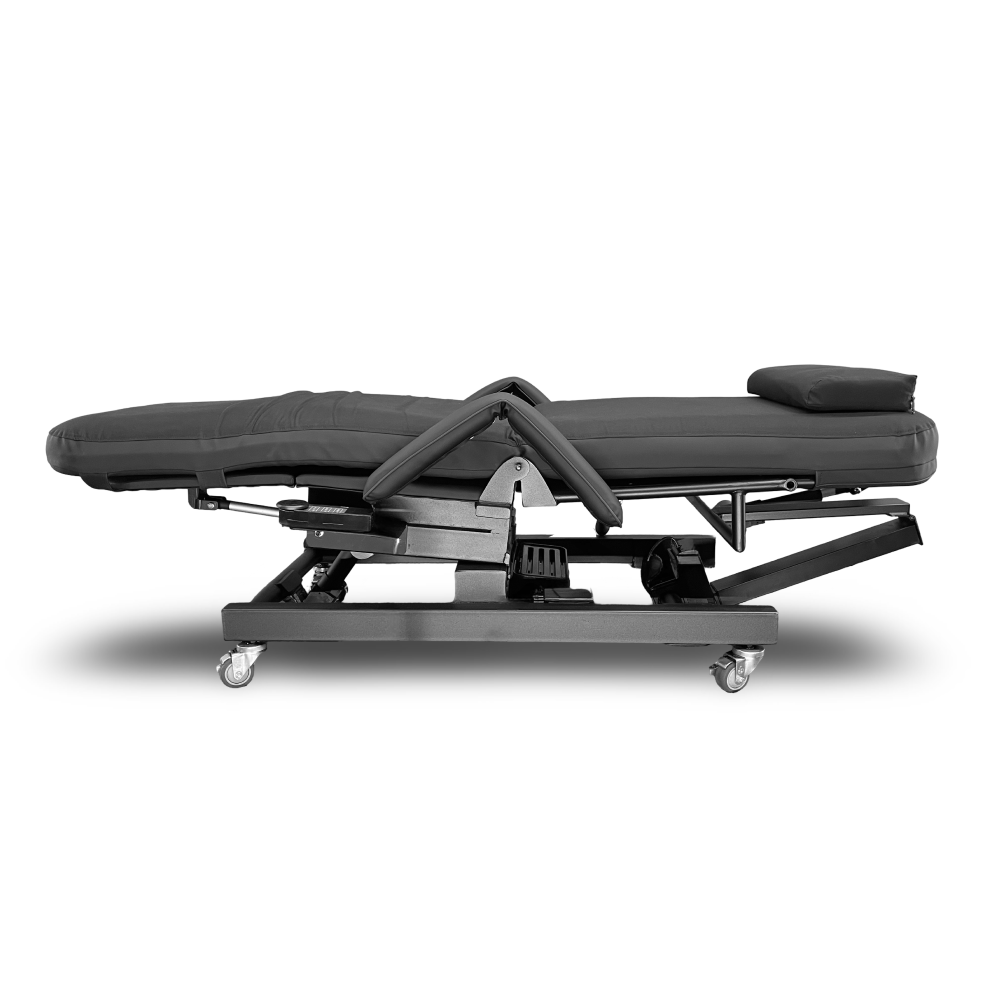 A black electric massage table with a padded treatment bed, adjustable frame, and caster wheels, shown from a side profile on a white background. Zero Gravity Chair 4 Special Needs Computers.