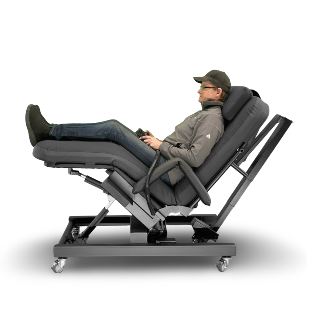 A man reclining in a fully adjustable black massage and therapy chair on a wheeled base, shown from a side profile against a white background. Zero Gravity Chair 4 Special Needs Computers.