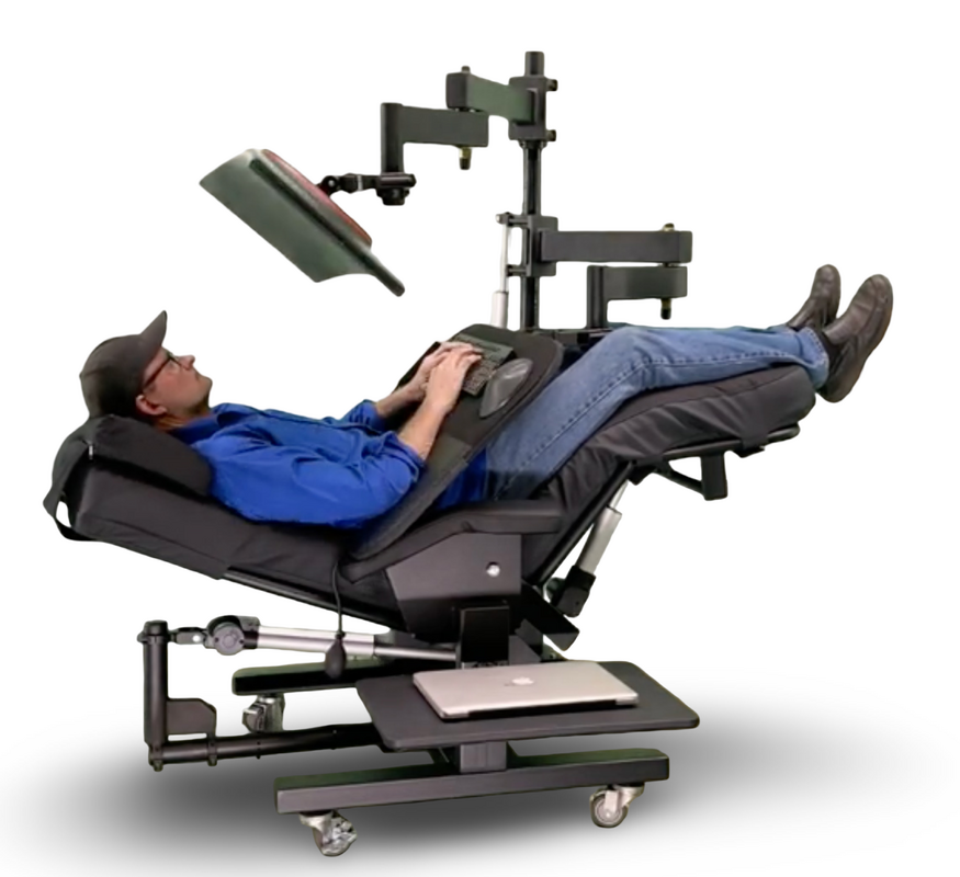 A reclining medical-style chair with a mounted arm, screen, and adjustable base, shown with a person lying down on a white studio background.  Zero Gravity Workstation 1c. Special Needs Computers Canada.